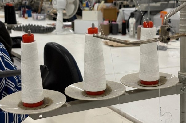 Drie klossen wit garen op een naaimachine in een atelier