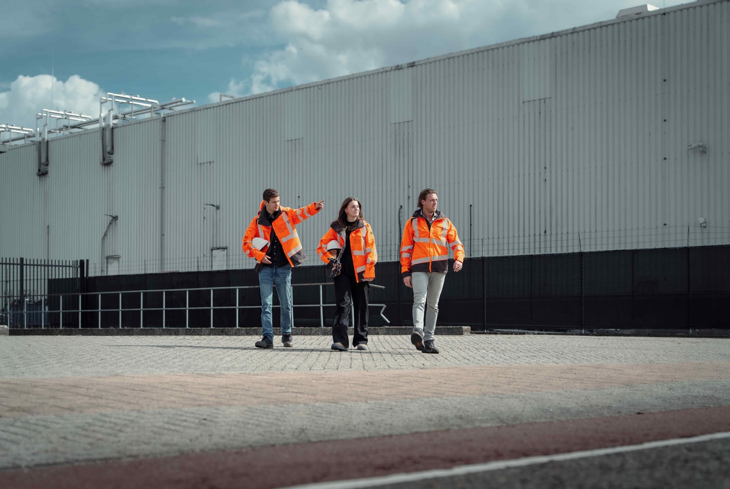 Drie collega’s van Diks Process Support in oranje werkjassen lopen langs een fabriekshal
