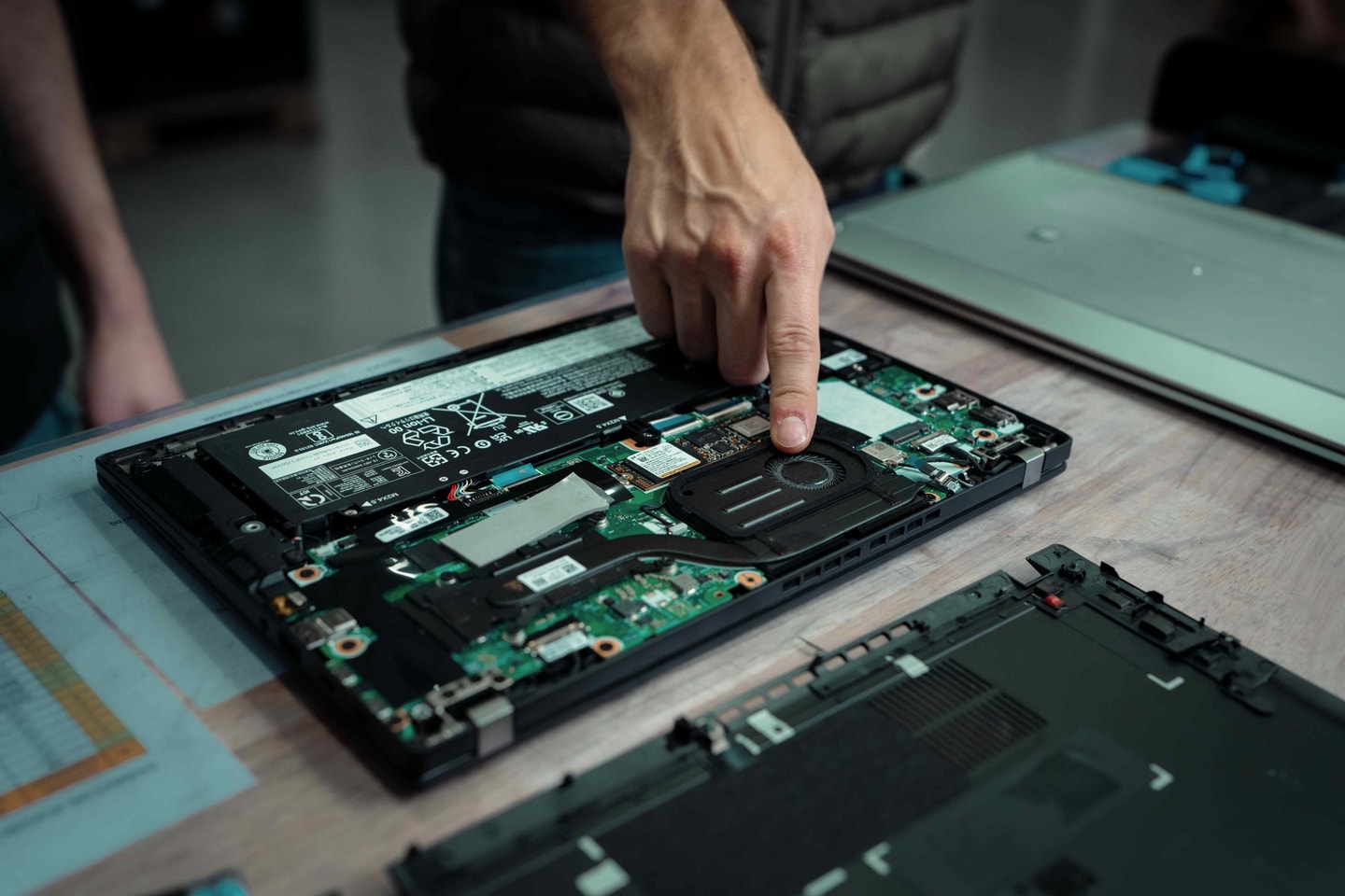 Vinger wijst een onderdeel aan in een opengewerkte laptop
