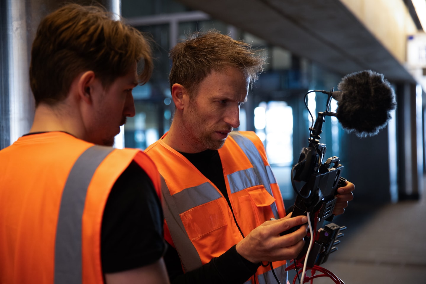 Twee mannen in oranje hesje met een videocamera met microfoon